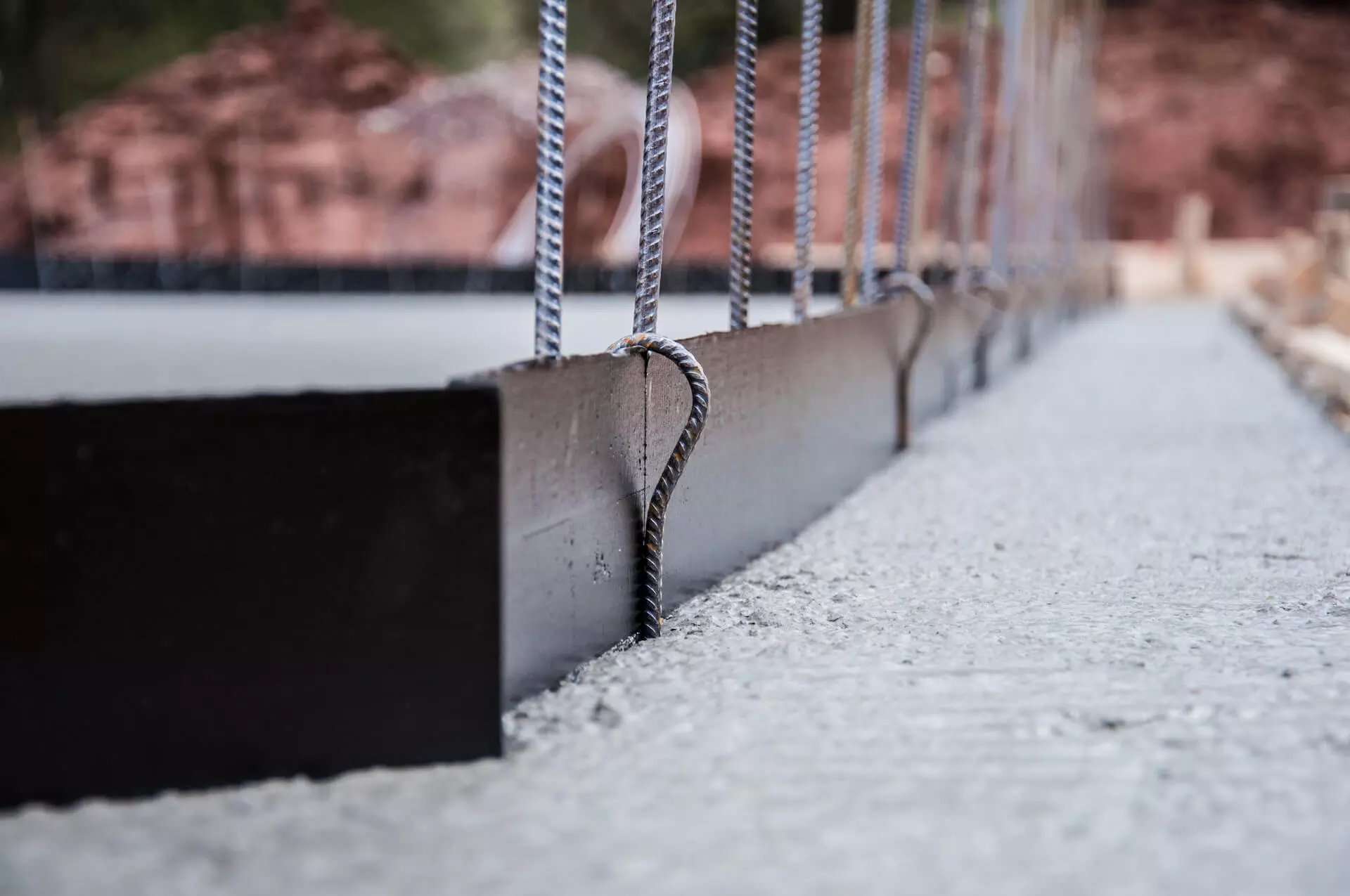 Nahaufnahme einer Betonbodenplatte mit eingebauten Stahlbewehrungsstäben und Schalung für ein Fertighaus von FingerHaus