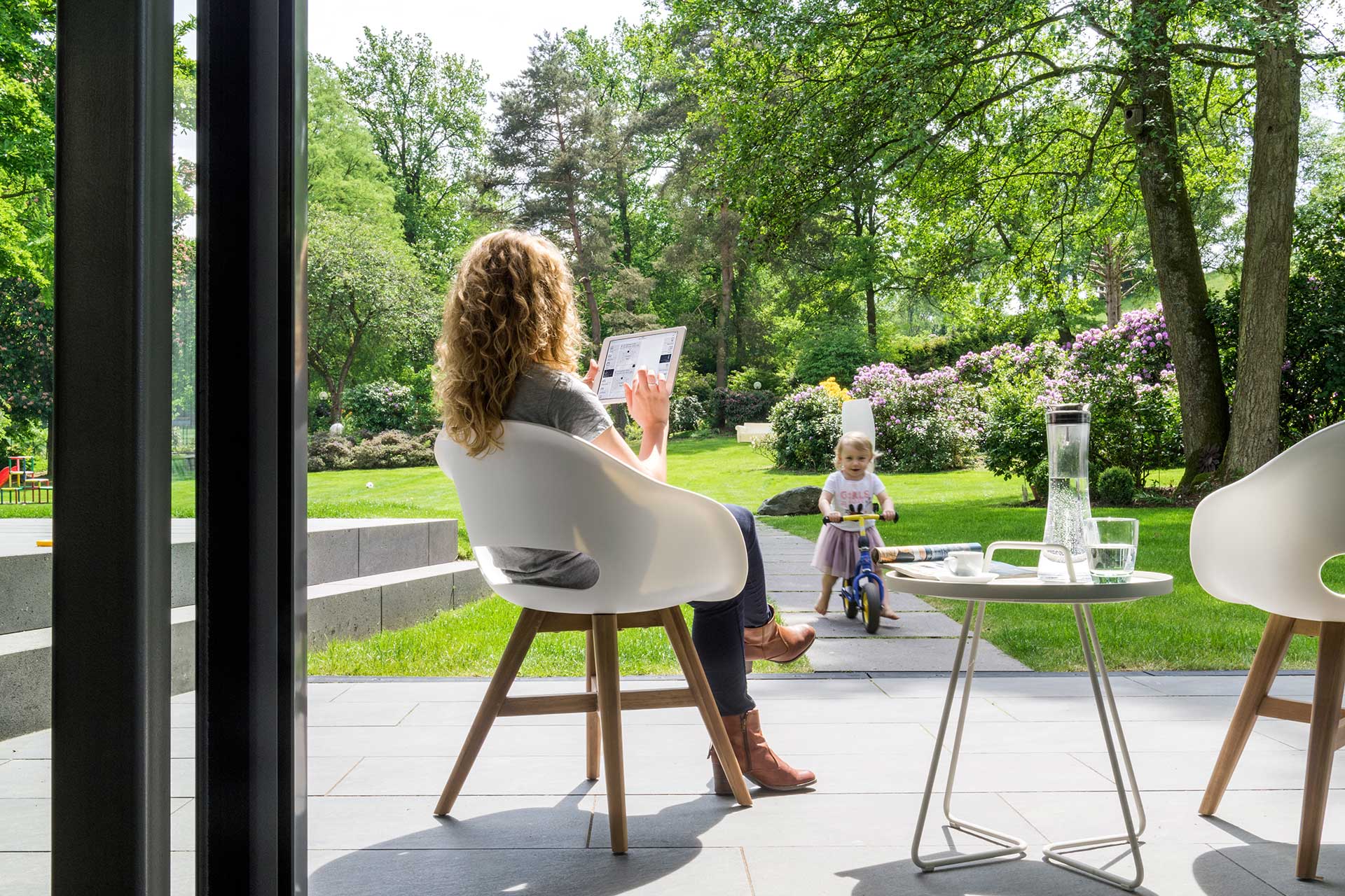 Garten mit Frau und Kind, Frau Steuert SmartHome Tablet