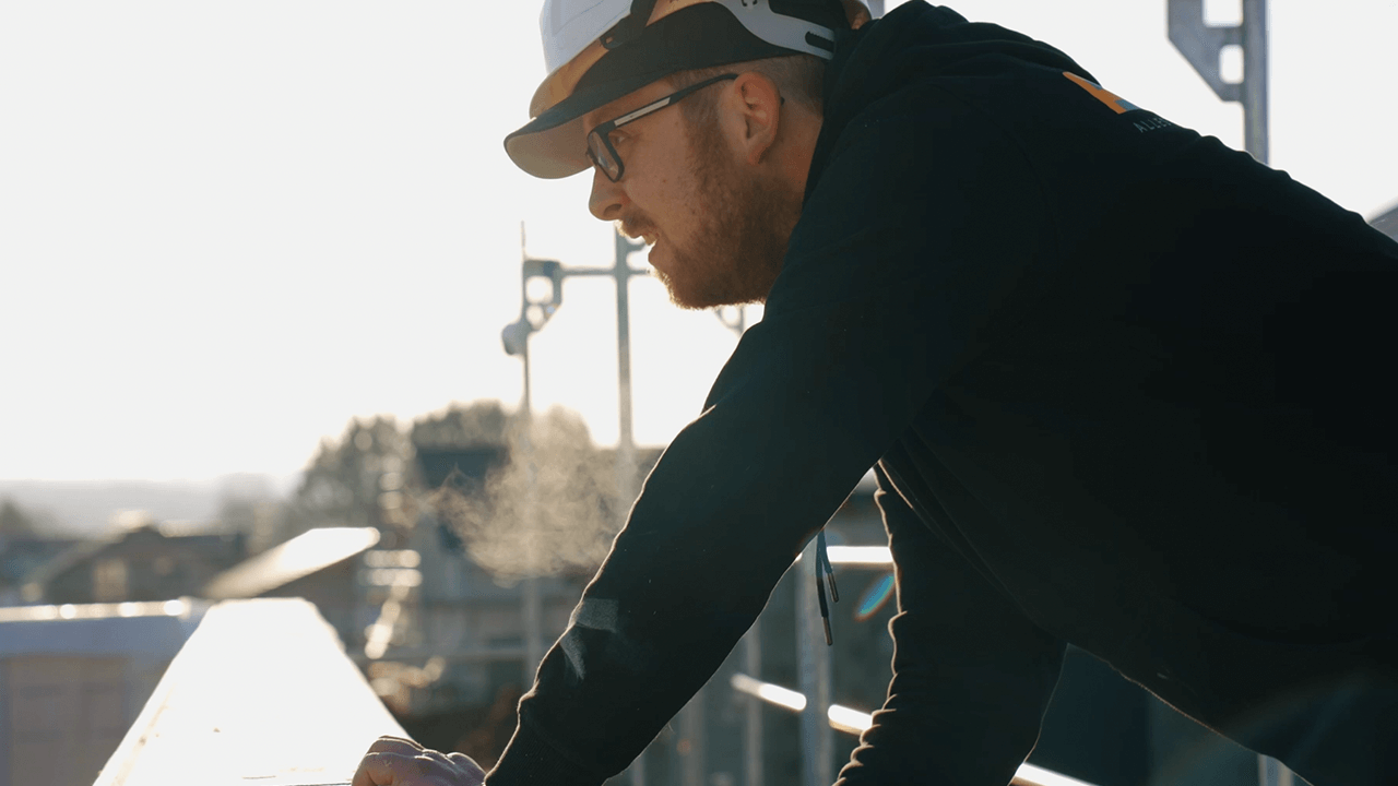 Thumbnail eines Expertenvideos von FingerHaus, ein Bauleiter mit Schutzhelm und Bauplänen auf einer Baustelle.