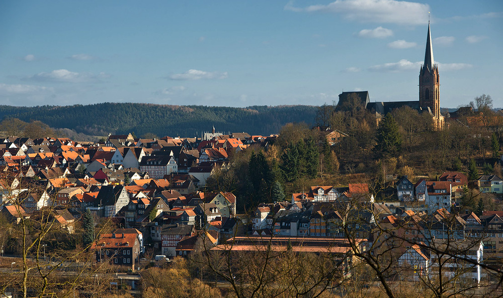 Blick über die Dächer und Altstadt von Frankenberg mit Kirchturm und umliegender Hügellandschaft.