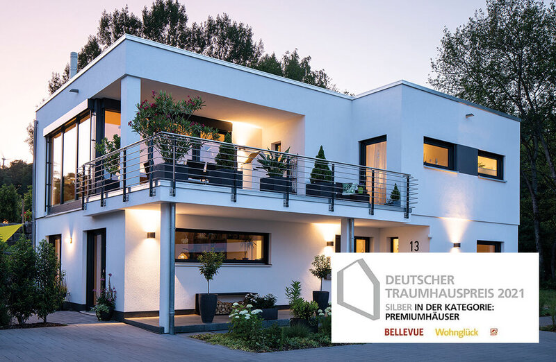 Modernes FingerHaus im Bauhausstil mit Flachdach, klaren Linien und großer Terrasse am Abend; daneben das Siegel „Deutscher Traumhauspreis 2021 – Silber in der Kategorie Premiumhäuser“.