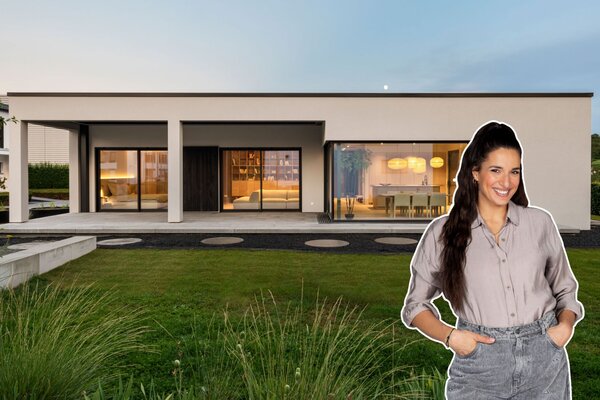 Der Musterhaus-Bungalow NIVO »Sally Edition« mit moderner Flachdacharchitektur, überdachter Terrasse und großzügigen Fensterfronten. Im Vordergrund ist Food-Bloggerin Sally Özcan zu sehen.