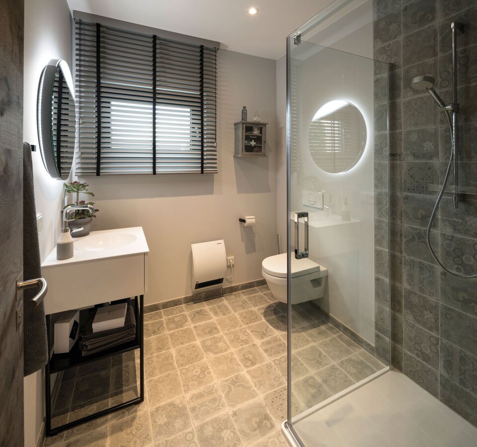 Modernes Gäste-WC mit Dusche, Waschtisch und großem Spiegel im Musterhaus ALTERO in Gießen.