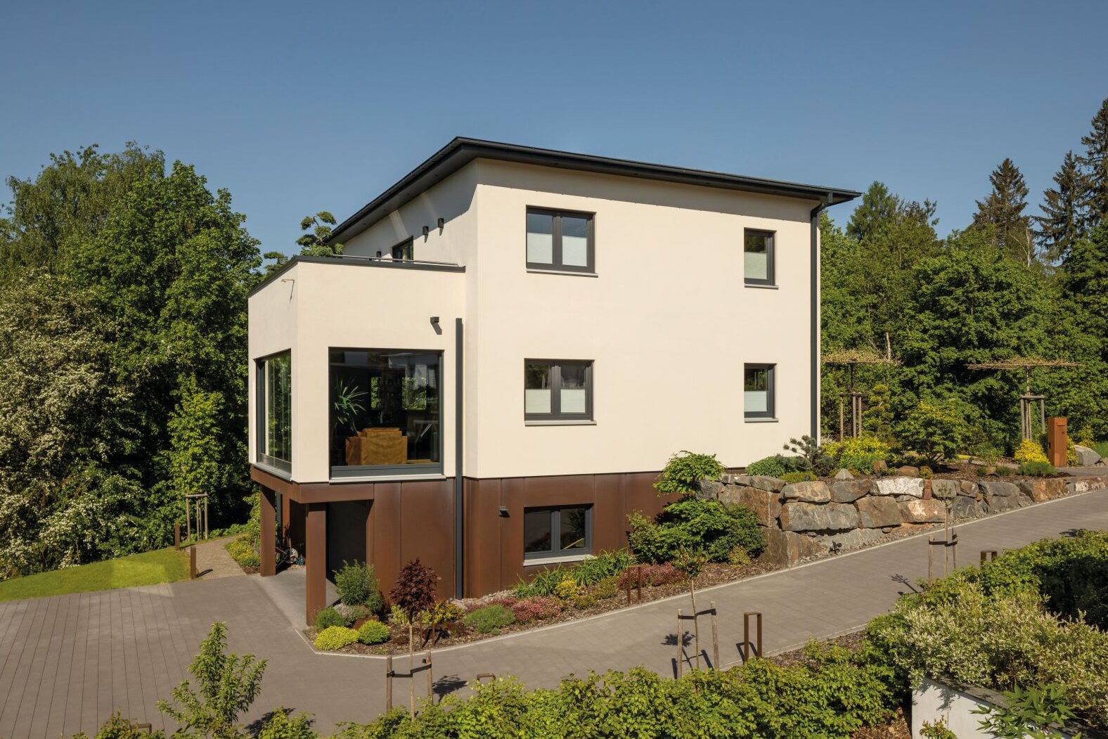 Modernes FingerHaus mit Flachdach, klarer Architektur und integrierter Garage, umgeben von Garten und Natur.