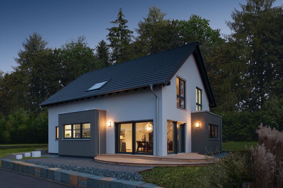Abendstimmung am Musterhaus NEO 312 in Bad Vilbel – moderne Architektur mit großen Fenstern, beleuchteter Terrasse und harmonischer Fassadengestaltung.