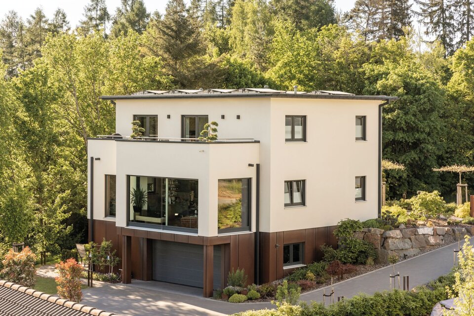 Modernes, frei geplantes FingerHaus mit klaren Linien, großzügigen Fensterflächen und integrierter Garage, eingebettet in grüne Umgebung.