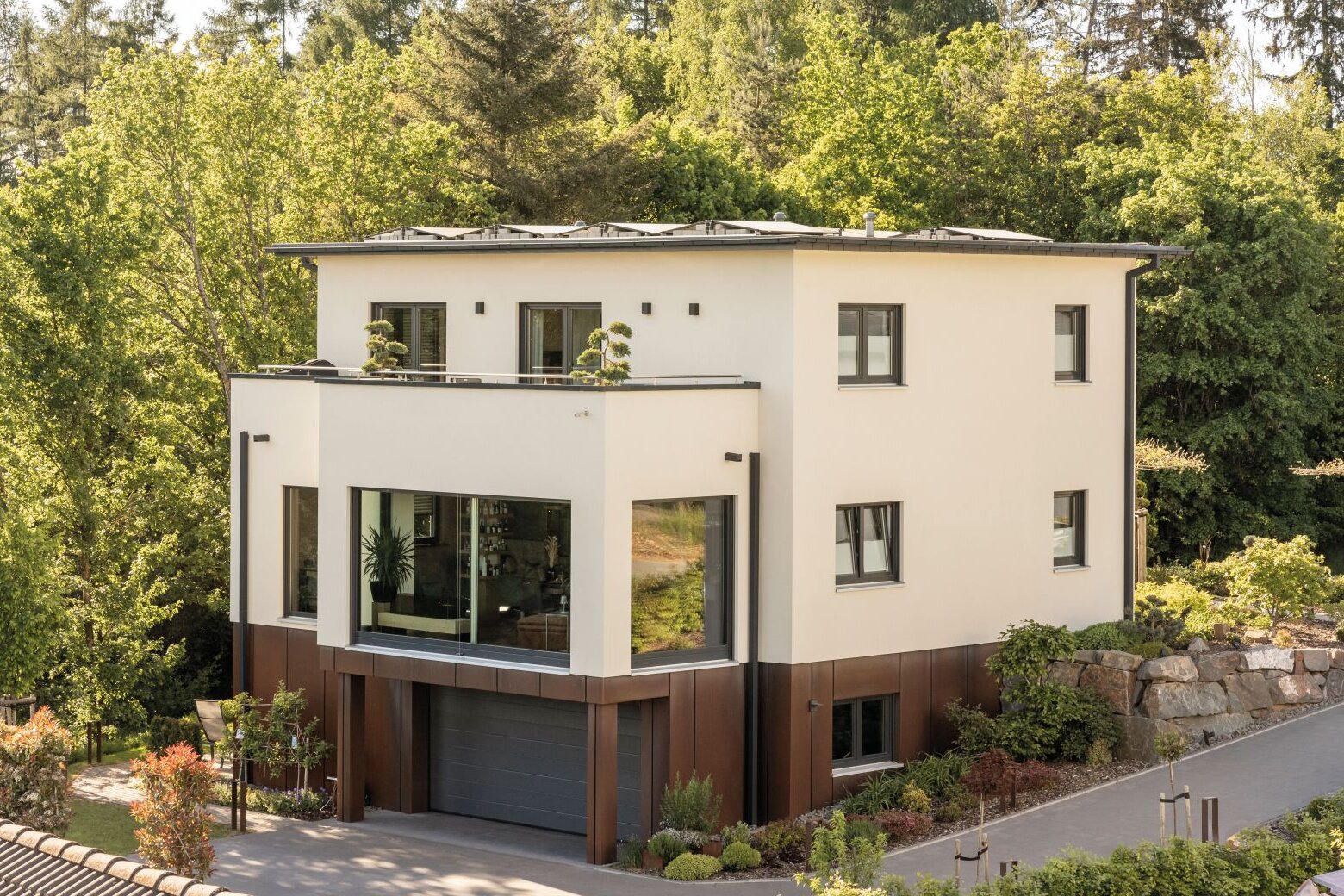 Modernes, frei geplantes FingerHaus mit klaren Linien, großzügigen Fensterflächen und integrierter Garage, eingebettet in grüne Umgebung.