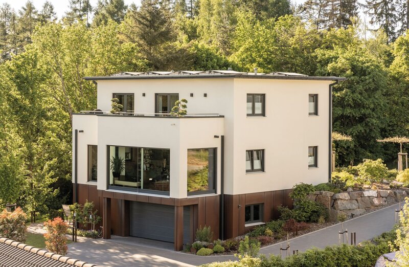 Modernes, frei geplantes FingerHaus mit klaren Linien, großzügigen Fensterflächen und integrierter Garage, eingebettet in grüne Umgebung.