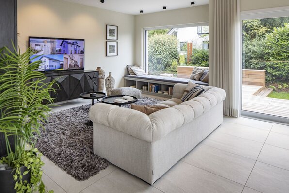 Wohnzimmer im FingerHaus-Musterhaus MEDLEY in Mannheim mit großzügiger Sofalandschaft, großen Fensterflächen, direktem Zugang zur Terrasse und heller, moderner Wohnraumgestaltung.