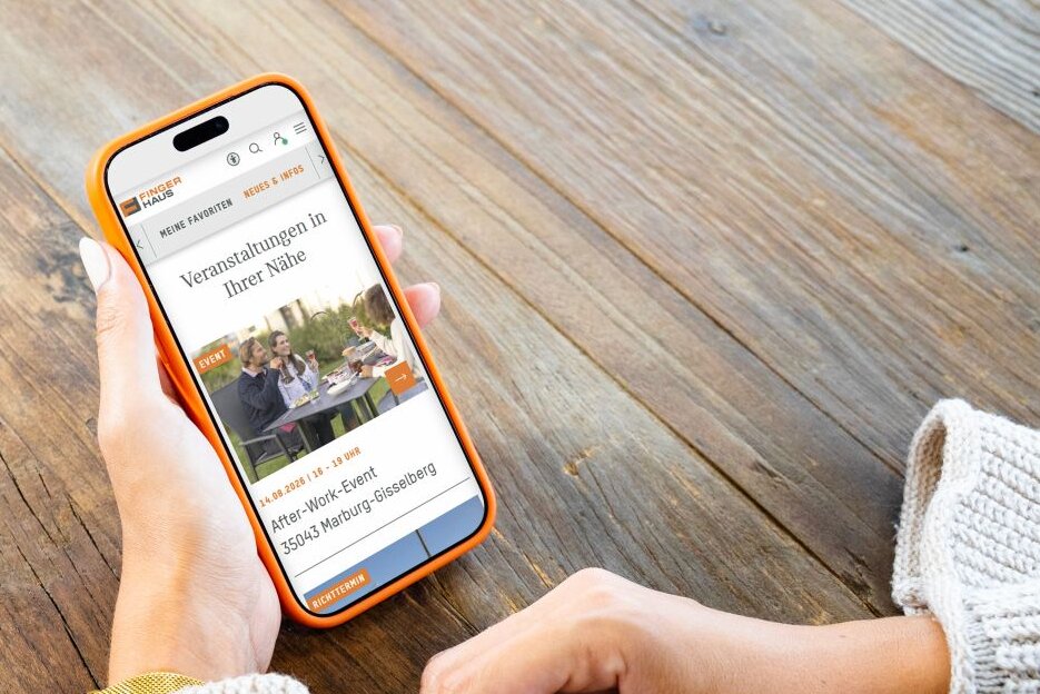 Person hält ein Smartphone mit dem FingerHaus+-Account in den Händen. Auf dem Display sind Veranstaltungen in der Nähe für Bauinteressierte zu sehen.