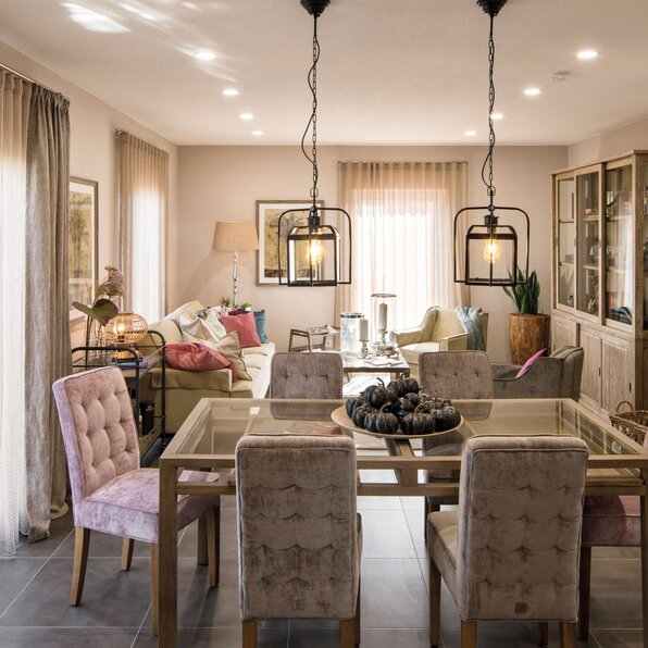 Essbereich mit Glas-Esstisch und Polsterstühlen im Musterhaus UNO 2.0 in Leipzig, Blick ins Wohnzimmer mit gemütlicher Einrichtung.