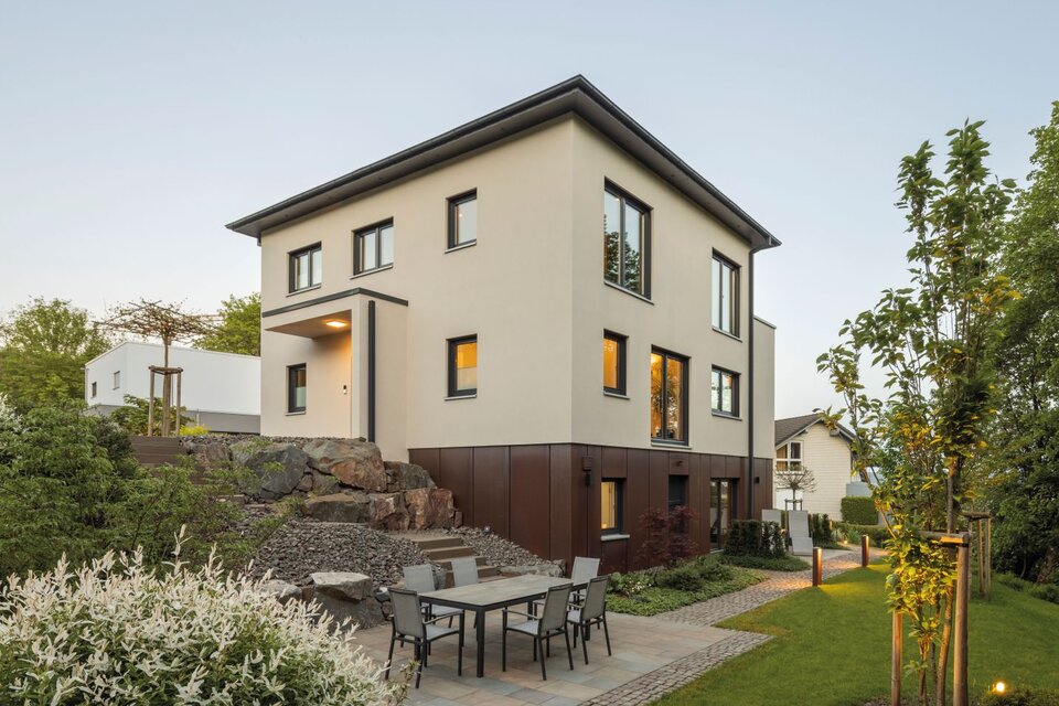 Frei geplantes FingerHaus mit moderner Fassade und großzügigem Gartenbereich, ergänzt durch eine gemütliche Terrasse mit Sitzgruppe.
