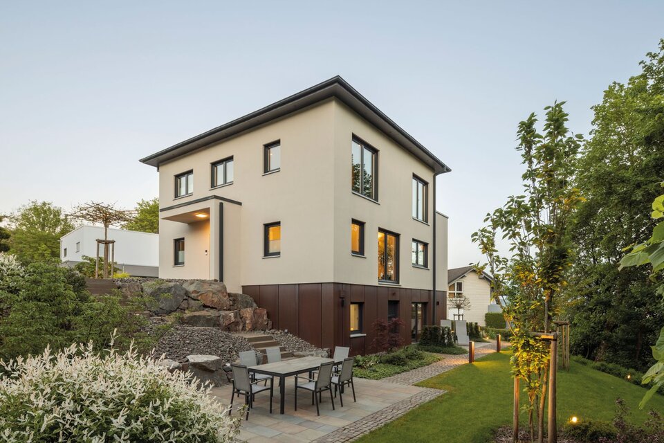 Frei geplantes FingerHaus mit moderner Fassade und großzügigem Gartenbereich, ergänzt durch eine gemütliche Terrasse mit Sitzgruppe.