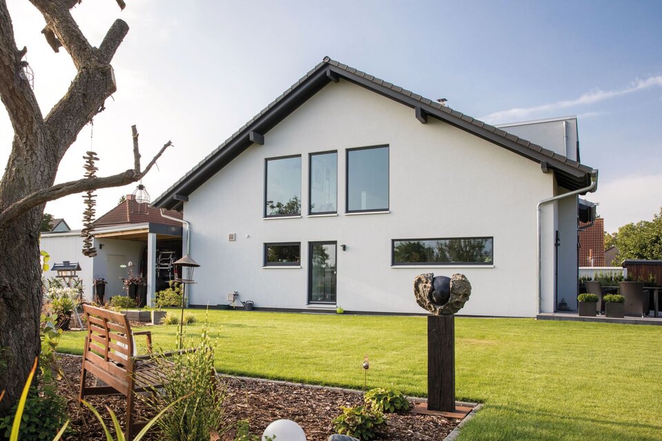 Großzügige Gartenansicht eines frei geplanten FingerHaus mit Sitzbank, Beeten und moderner Architektur.