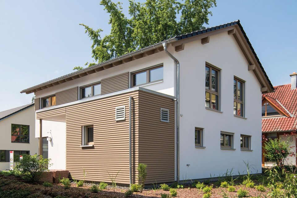 Außenansicht des Musterhauses MEDLEY in Fellbach mit moderner Holzverkleidung, klaren Linien und Pultdach-Anbau.