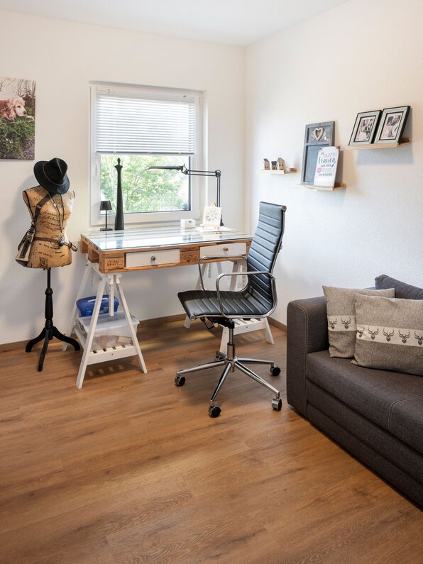 Arbeitszimmer in einem frei geplanten Kundenhaus mit Schreibtisch, Bürostuhl und Fenster.