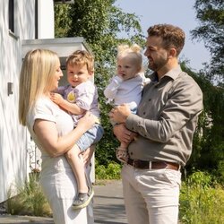 Eltern stehen mit ihren zwei kleinen Kindern vor ihrem frei geplanten FingerHaus im Garten. Das moderne Einfamilienhaus mit heller Fassade und Holzterrasse bildet den Hintergrund.