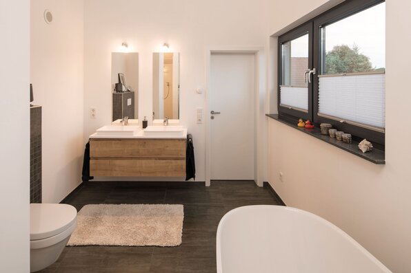 Modernes Bad im Obergeschoss eines FingerHaus-Hauses mit freistehender Badewanne, Doppelwaschbecken und großem Fenster.