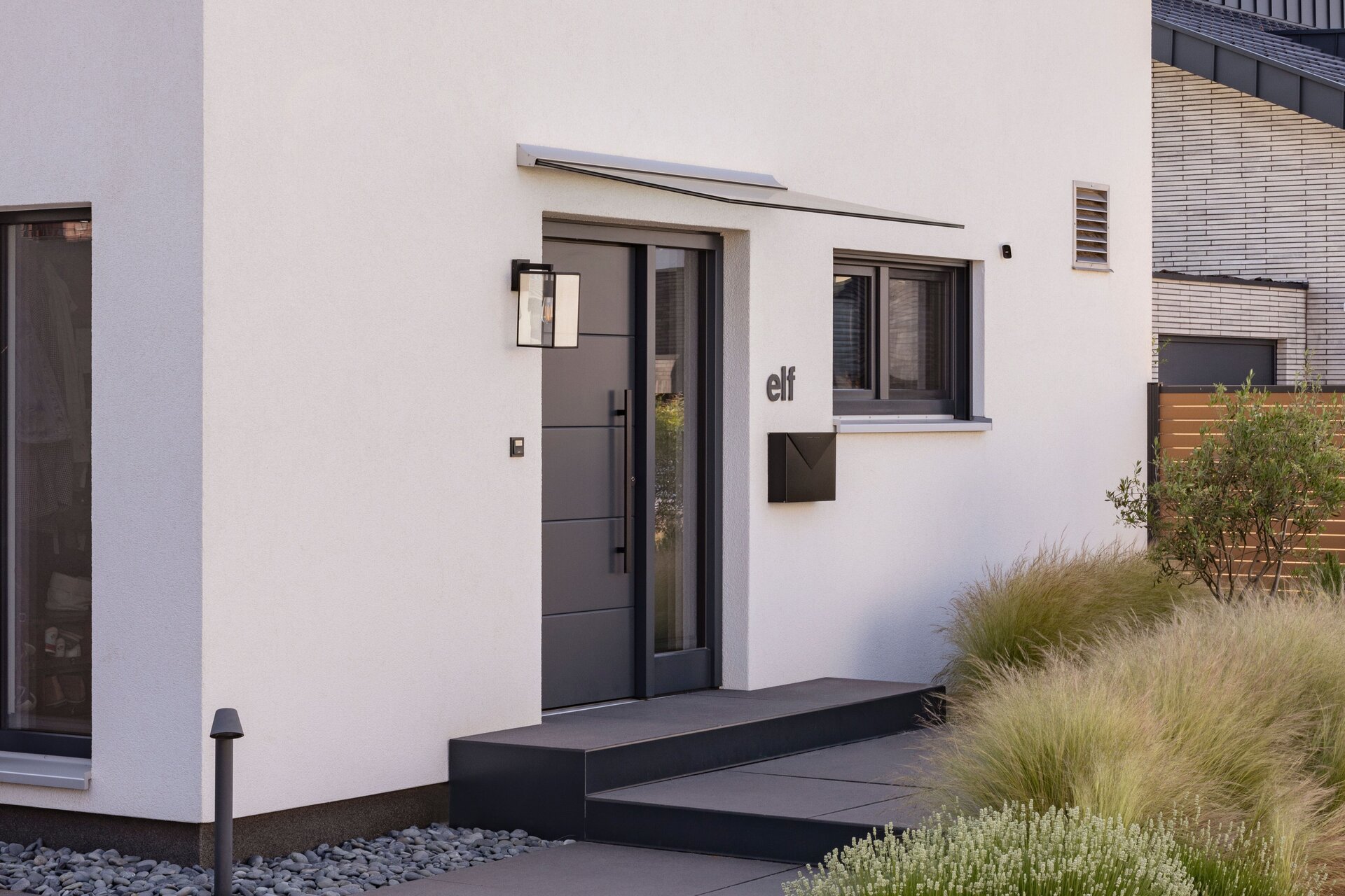 Eingangsbereich eines frei geplanten Einfamilienhauses mit moderner Haustür und Satteldach