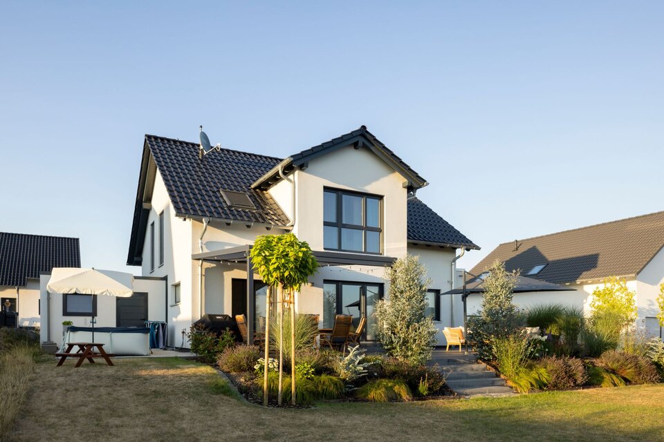Außenansicht eines Einfamilienhauses SENTO 403 mit Satteldach, Terrassenüberdachung und Gartenanlage