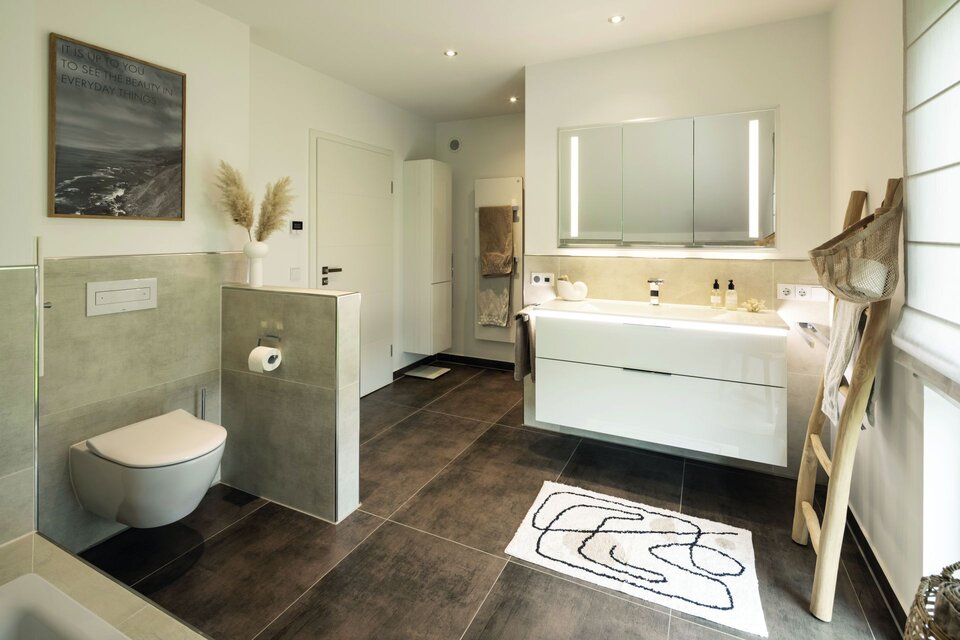 Modernes Bad mit WC, Doppelwaschtisch und großem Spiegel. Graue Fliesen, Holzdetails und Dekoration mit Trockenblumen schaffen ein harmonisches Gesamtbild.
