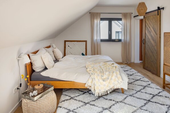 Frei geplantes Schlafzimmer im FingerHaus mit gemütlichem Teppich, Holzbett und modernen Details.