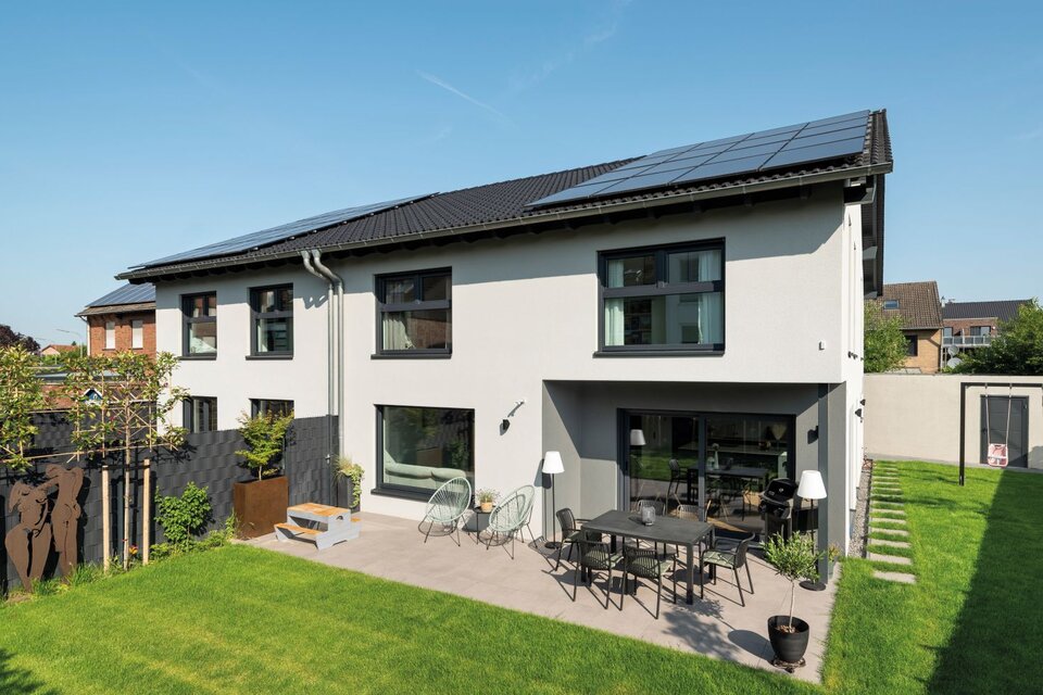 Doppelhaushälfte mit Satteldach, Photovoltaikanlage und Terrasse mit Sitzgruppe im Garten