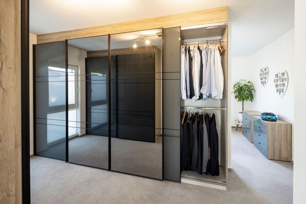 Schlafzimmer mit integrierter Ankleide und großem Kleiderschrank in einem frei geplanten Finger-Haus.