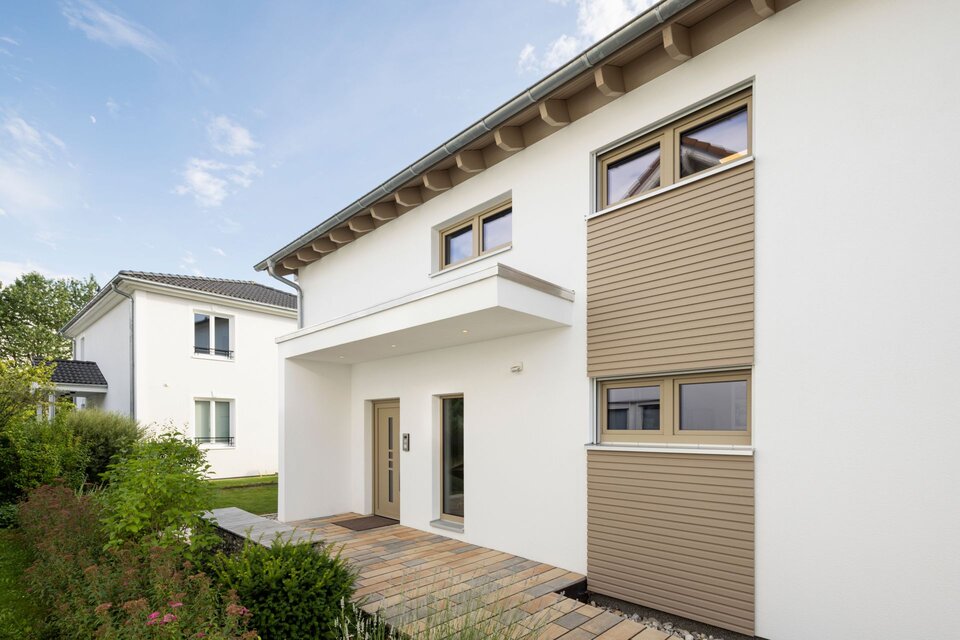 Moderner Eingangsbereich des Musterhauses MEDLEY 300 B in Poing mit überdachtem Zugang, klarer Architektur und stilvollen Fassadenelementen.