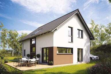 Modernes zweigeschossiges Fertighaus mit Satteldach, großen Fenstern und Terrasse mit Gartenmöbeln in grüner Umgebung