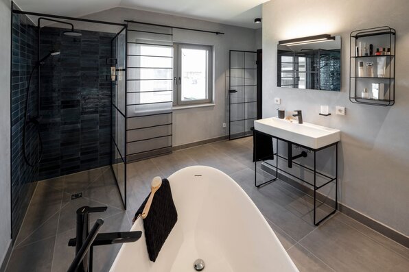 Modernes Badezimmer im FingerHaus ARTIS 400 Musterhaus Schwarzwald mit freistehender Badewanne, ebenerdiger Dusche, großem Waschtisch und stilvollem Design.