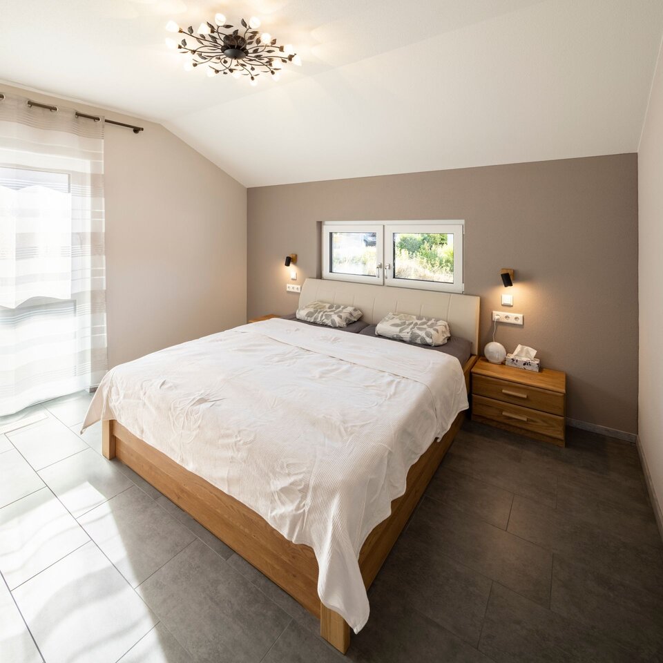Helles Schlafzimmer mit großem Bett, weichen Textilien und warmem Tageslicht.