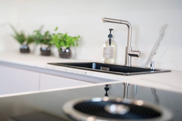 Detailaufnahme einer modernen Küchenspüle mit Edelstahlarmatur im Musterhaus MEDLEY 300 B in Frankenberg.