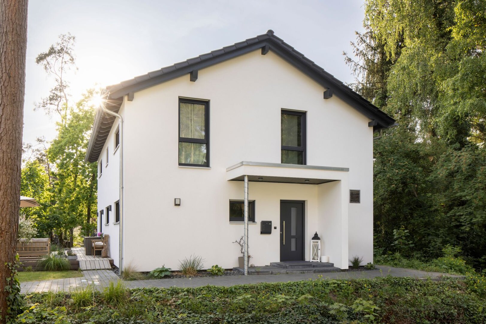 Modernes frei geplantes FingerHaus mit Satteldach, klarer Fassadengestaltung und gemütlicher Terrasse im Garten.