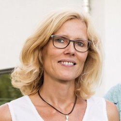 Zwei Personen stehen lächelnd im Garten vor einem frei geplanten FingerHaus mit großer Terrasse und moderner Fassadengestaltung.