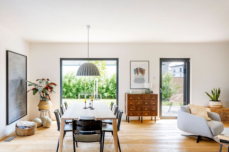 Helles Esszimmer in einem frei geplanten FingerHaus mit großem Holztisch, modernen Stühlen und stilvollem Design.