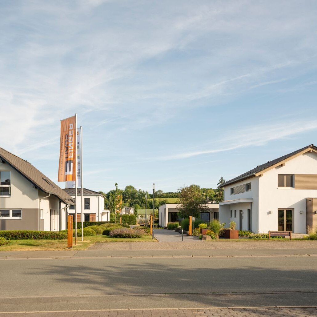 Vier moderne Musterhäuser im FingerHaus Musterhaus-Park mit klaren Fassaden und gepflegten Vorgärten.