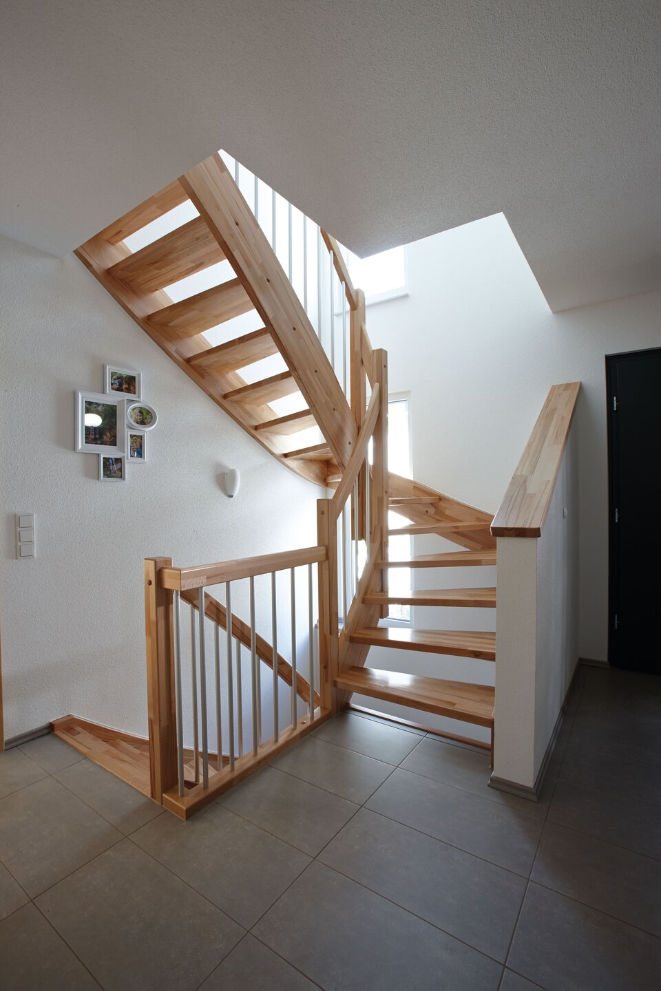 Holztreppe mit offenem Geländer in hellem Treppenhaus