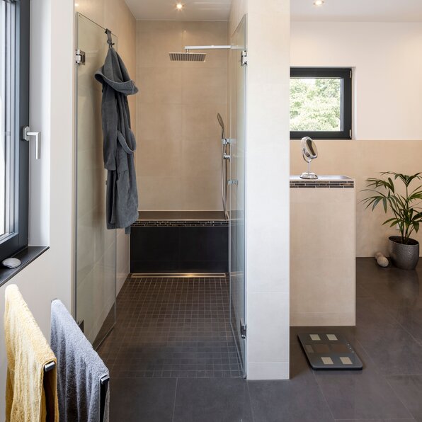 Modernes Badezimmer mit bodengleicher Dusche, hellen Fliesen und stilvoller Ausstattung.