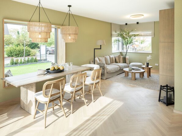 Heller Wohn- und Essbereich im Musterhaus JUNO von FingerHaus mit großen Fenstern, Holzboden, Naturtönen und gemütlicher Einrichtung im modernen Stil.