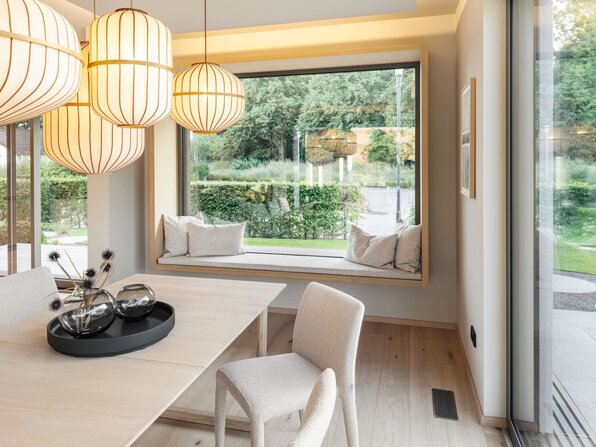 Essbereich im FingerHaus Musterhaus NIVO in Frankenberg mit Esstisch, Pendelleuchten und großer Fensternische mit gepolsterter Sitzbank.