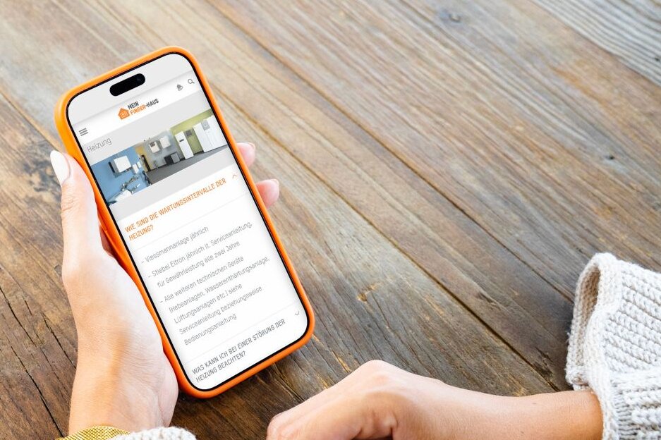 Person hält ein Smartphone mit dem FingerHaus Serviceportal in den Händen. Auf dem Display sind häufig gestellte Fragen für Hausbesitzer zu sehen.