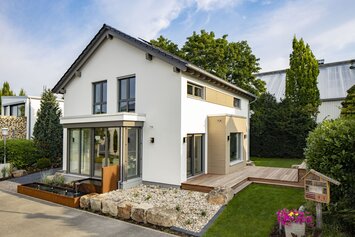 Modernes FingerHaus MEDLEY Musterhaus in Mannheim mit Holzakzenten, Wintergarten und gepflegtem Gartenbereich.