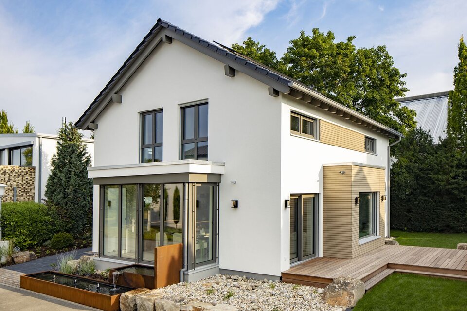 Modernes FingerHaus MEDLEY Musterhaus in Mannheim mit Holzakzenten, Wintergarten und gepflegtem Gartenbereich.