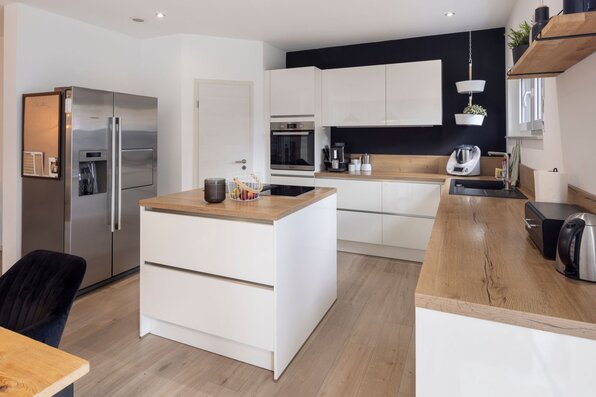 Frei geplantes FingerHaus mit moderner Küche, Kochinsel, Holzarbeitsflächen und großem Kühlschrank.