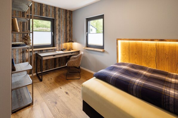 Frei geplantes FingerHaus mit gemütlichem Gästezimmer, Holzdetails und Schreibtisch.