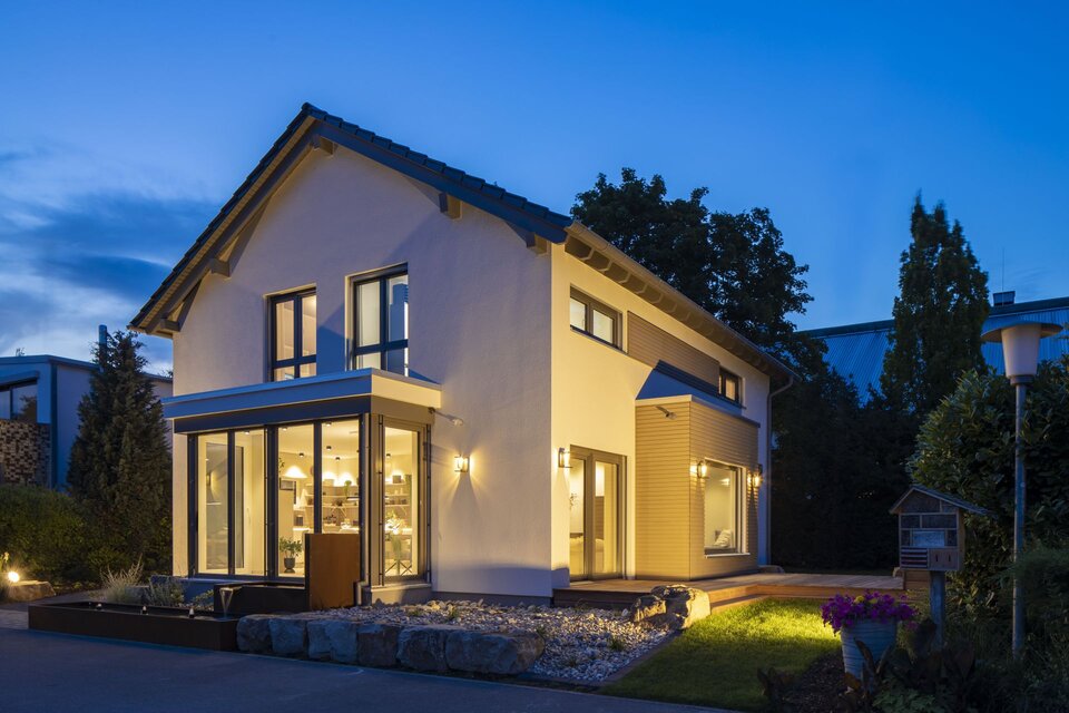Abendaufnahme des MEDLEY Musterhauses Mannheim mit beleuchteter Glasfassade und stilvollem Außenbereich.