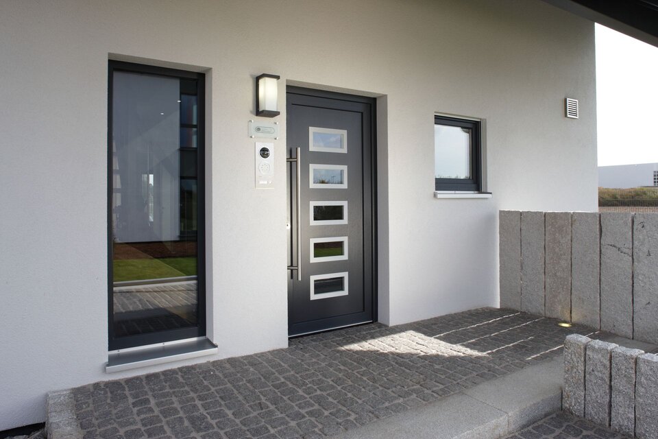 Moderner Eingangsbereich mit stilvoller Haustür und seitlichem Glasfenster im Musterhaus VIO 400 in Köln.