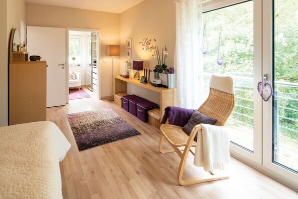Gemütliches Schlafzimmer mit Holzboden, Balkonzugang und warmen Farben in einem FingerHaus.