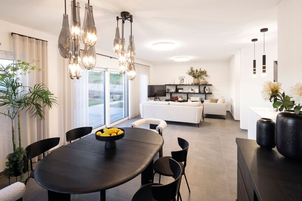 Offener Wohn- und Essbereich im Musterhaus TALO Fulda mit elegantem Esstisch, Designerleuchte und gemütlicher Sofaecke.